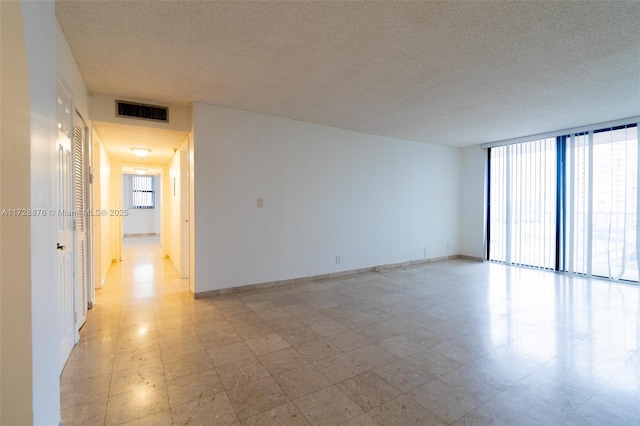 unfurnished room featuring a textured ceiling and expansive windows