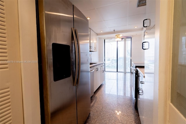 kitchen featuring appliances with stainless steel finishes, a wall of windows, and white cabinetry