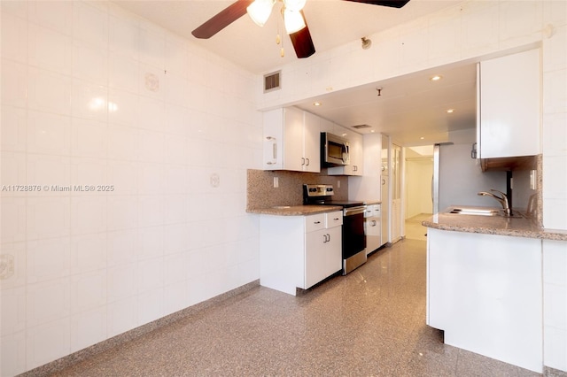 kitchen with appliances with stainless steel finishes, white cabinetry, tasteful backsplash, sink, and ceiling fan