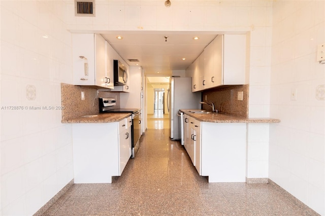 kitchen with stainless steel appliances, decorative backsplash, and white cabinetry