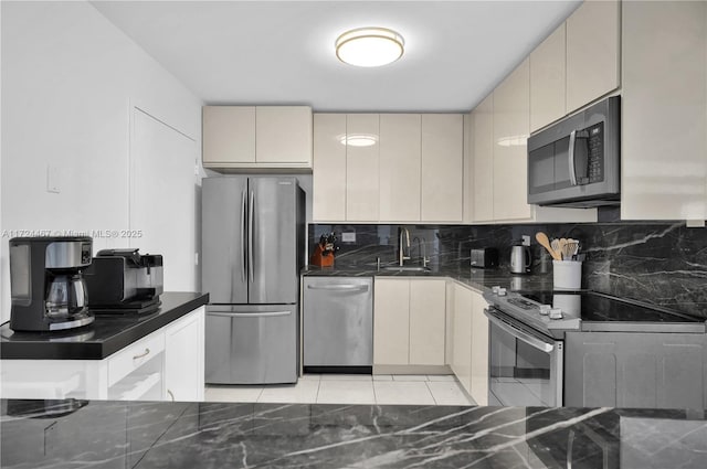 kitchen featuring tasteful backsplash, appliances with stainless steel finishes, light tile patterned flooring, and cream cabinets