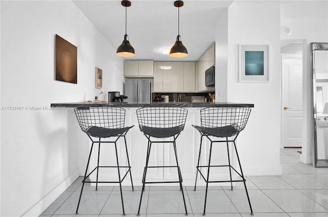 kitchen featuring a kitchen bar, decorative backsplash, stainless steel refrigerator, kitchen peninsula, and light tile patterned flooring