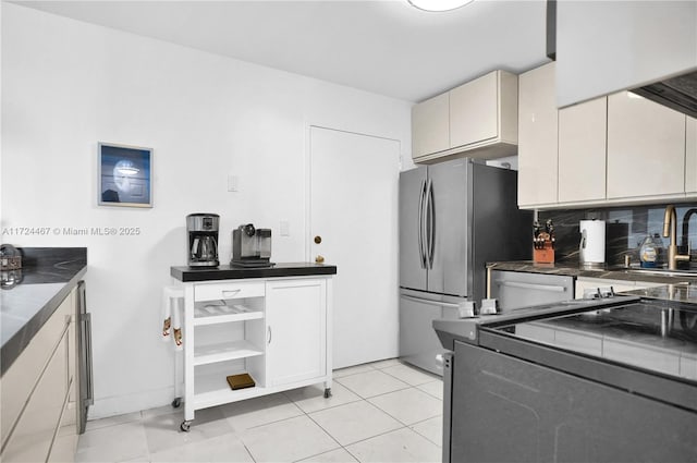 kitchen with light tile patterned floors, sink, backsplash, and stainless steel refrigerator