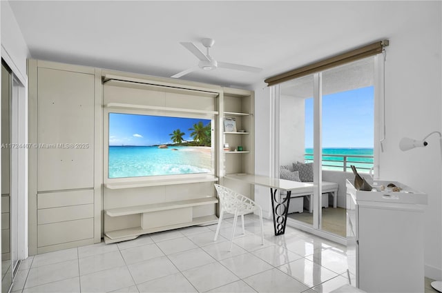 living room with ceiling fan, light tile patterned flooring, and a water view