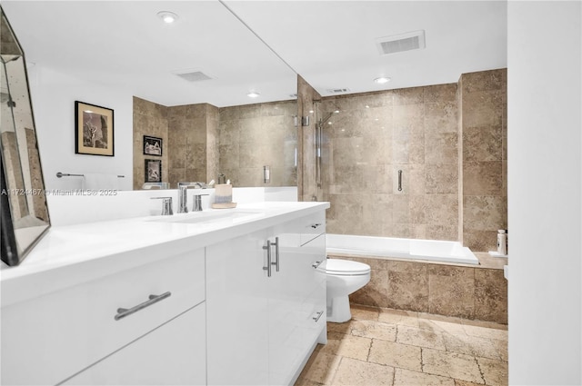 full bathroom featuring toilet, tile walls, tiled shower / bath, and vanity