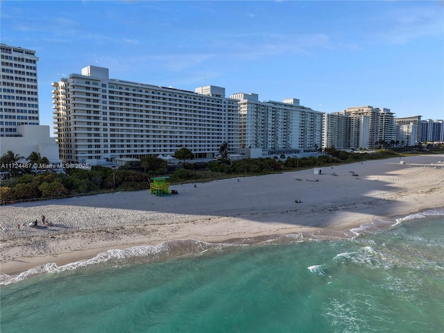 view of building exterior featuring a water view and a beach view