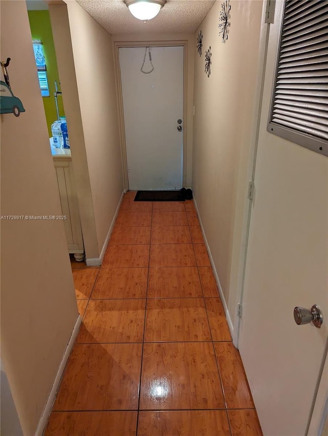 corridor featuring a textured ceiling and light tile patterned floors