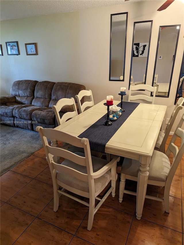 dining room with dark tile patterned floors and a textured ceiling