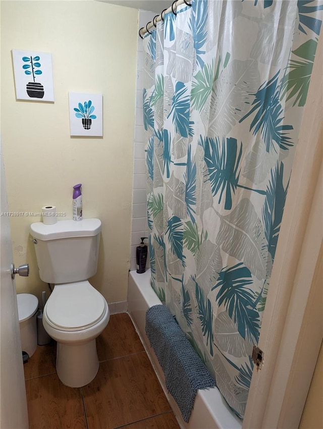 bathroom with wood-type flooring, toilet, and shower / tub combo