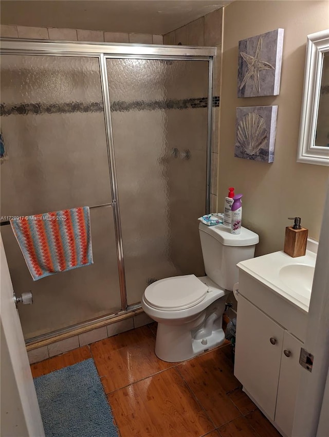 bathroom featuring an enclosed shower, vanity, toilet, and hardwood / wood-style floors