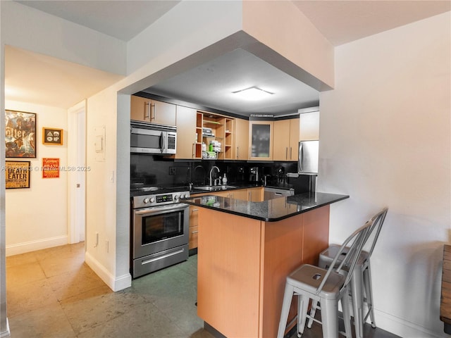 kitchen featuring appliances with stainless steel finishes, dark stone counters, decorative backsplash, a kitchen breakfast bar, and kitchen peninsula