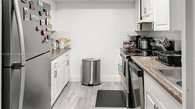 kitchen featuring appliances with stainless steel finishes, white cabinetry, decorative backsplash, light hardwood / wood-style floors, and sink