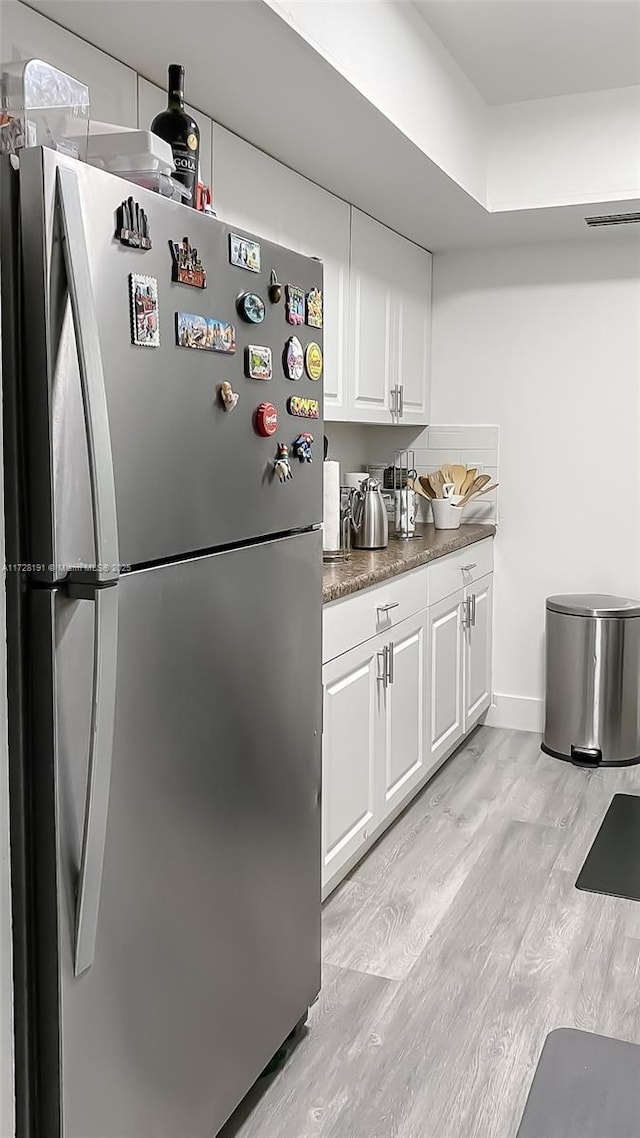 kitchen featuring white cabinets, light wood-type flooring, and stainless steel refrigerator