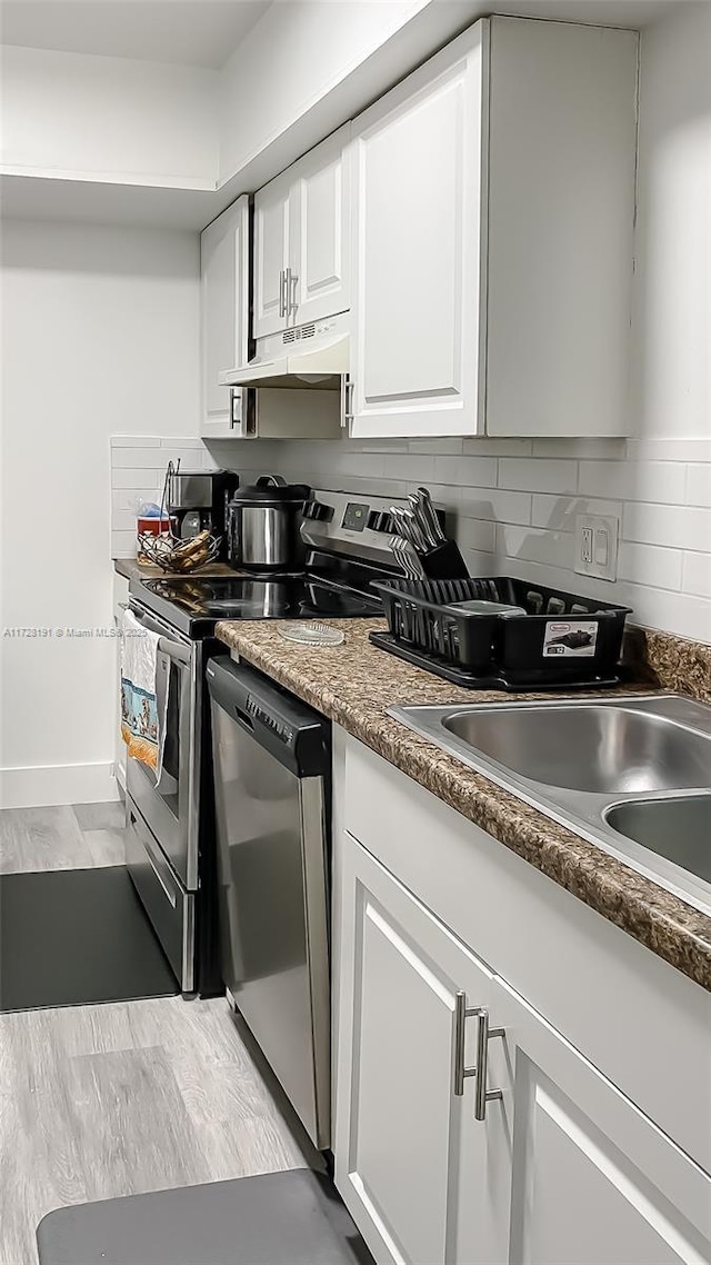 kitchen featuring backsplash, sink, white cabinetry, light wood-type flooring, and appliances with stainless steel finishes