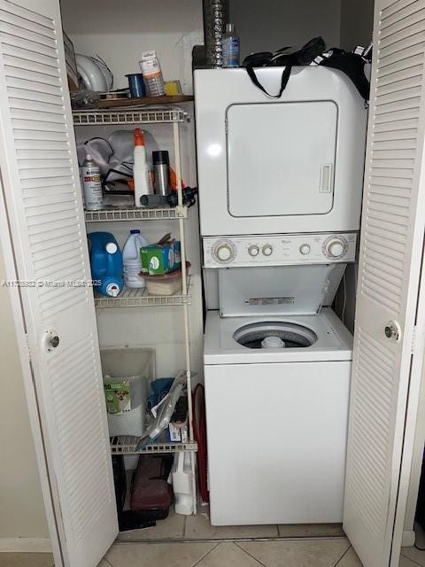 washroom with light tile patterned floors and stacked washer and dryer