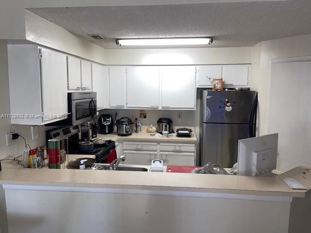 kitchen with a textured ceiling, kitchen peninsula, stainless steel appliances, and white cabinets