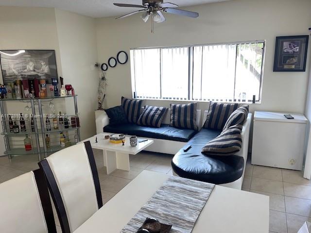 tiled living room featuring ceiling fan and plenty of natural light