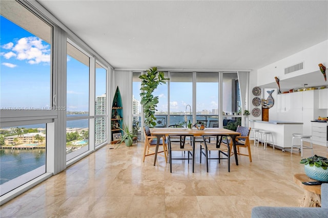 dining room with a healthy amount of sunlight, a wall of windows, and a water view