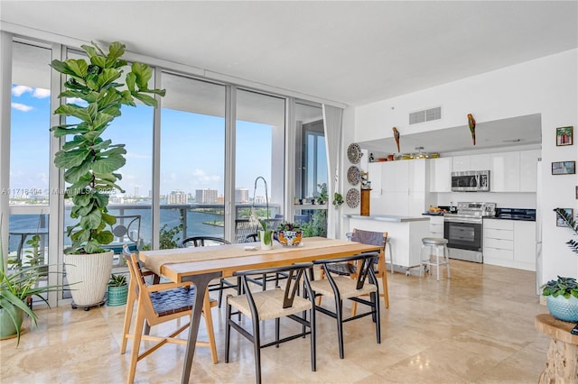 dining space with a water view and expansive windows