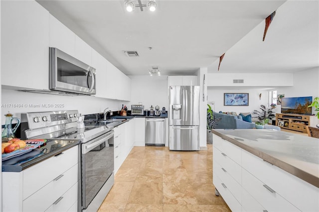 kitchen with white cabinets, appliances with stainless steel finishes, sink, and light tile patterned floors