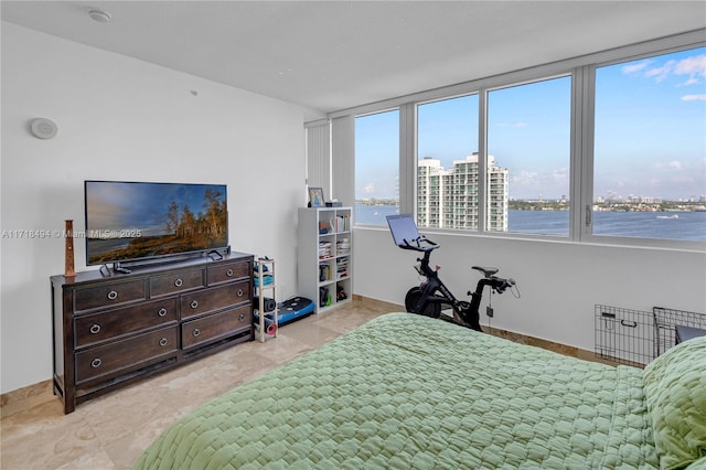 bedroom featuring a water view and multiple windows