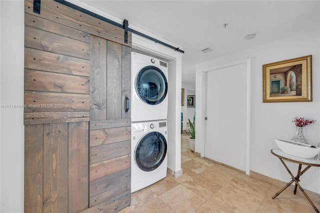 laundry room featuring stacked washer / drying machine and a barn door