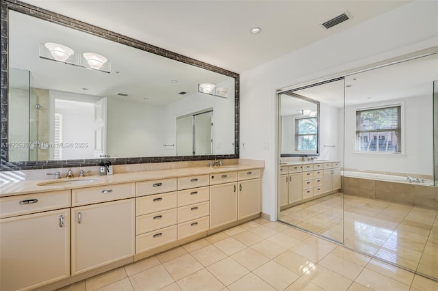 bathroom with tiled bath, vanity, and tile patterned flooring