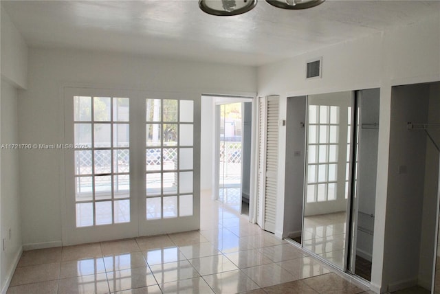 entryway featuring light tile patterned flooring, a healthy amount of sunlight, and french doors