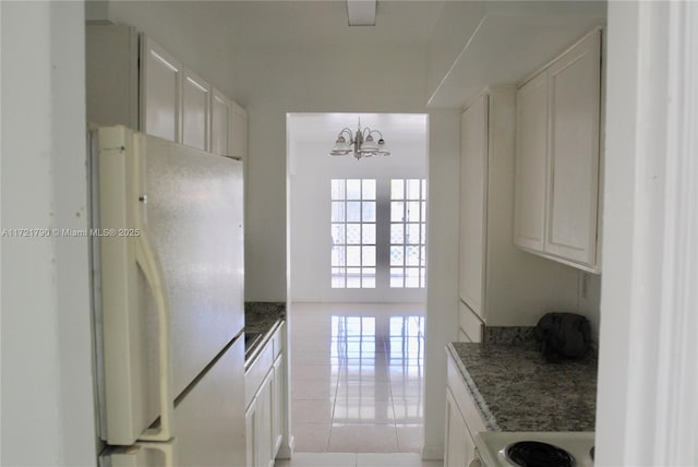 kitchen with decorative light fixtures, white cabinetry, white refrigerator, light tile patterned flooring, and stove