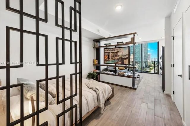 bedroom with floor to ceiling windows, hardwood / wood-style flooring, and stainless steel fridge