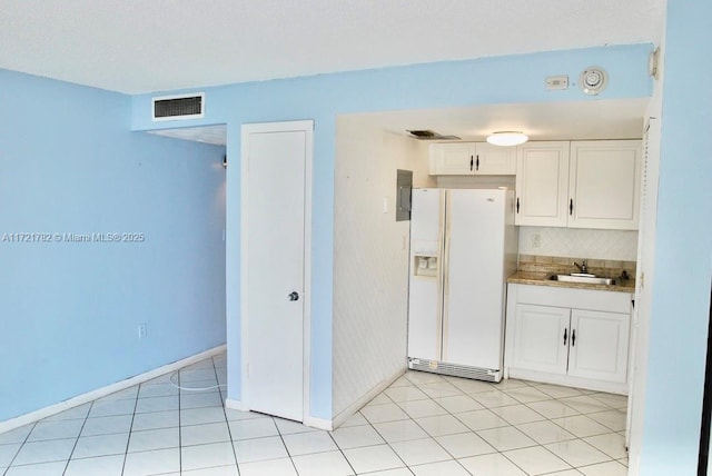 kitchen featuring light tile patterned flooring, white refrigerator with ice dispenser, white cabinets, and sink