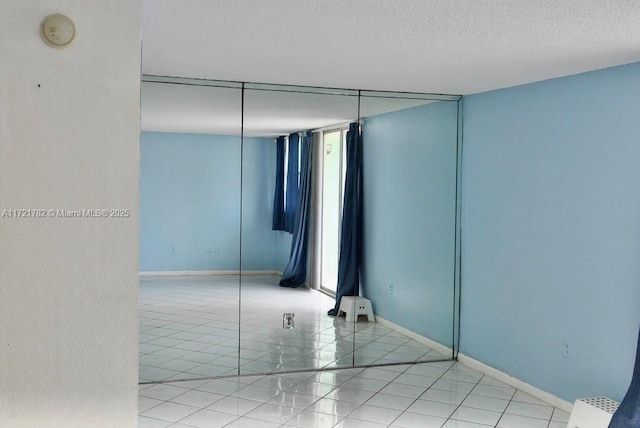 tiled empty room featuring a textured ceiling