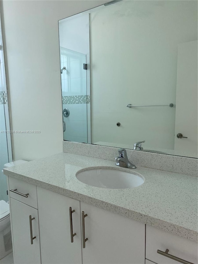 bathroom featuring toilet, vanity, and walk in shower