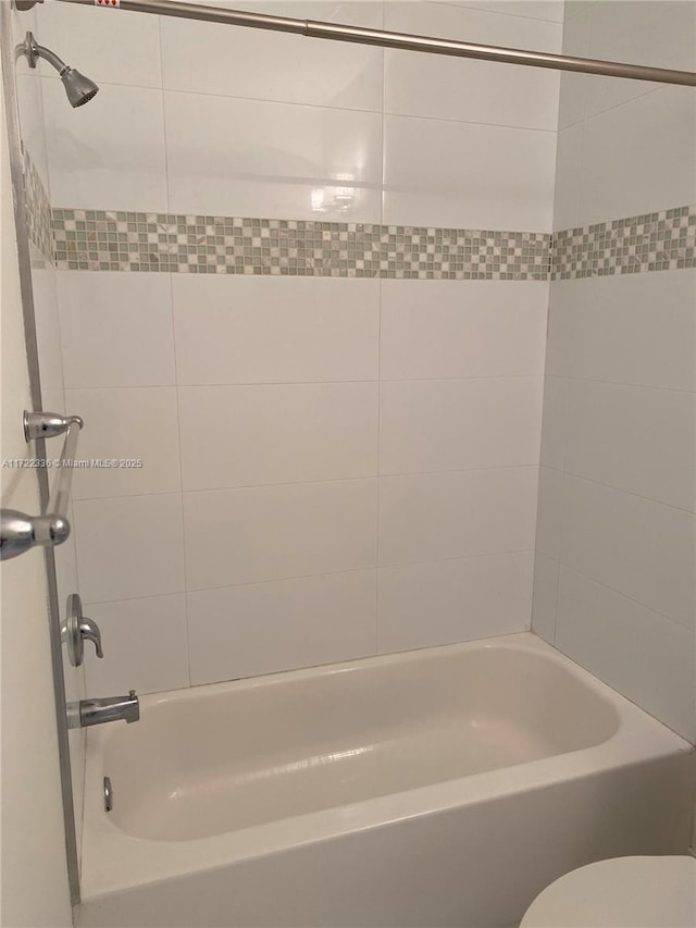 bathroom featuring toilet and tiled shower / bath