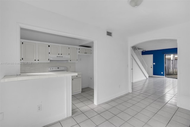 kitchen featuring light tile patterned floors, decorative backsplash, tile countertops, and white cabinetry