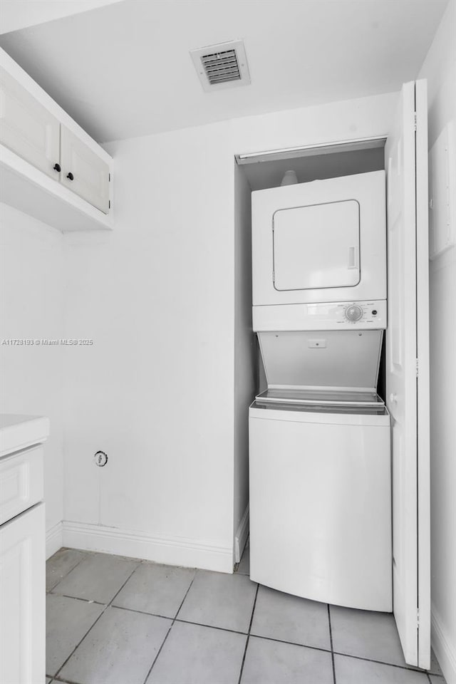 laundry room featuring light tile patterned floors and stacked washing maching and dryer