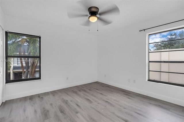 empty room with ceiling fan, plenty of natural light, and light wood-type flooring