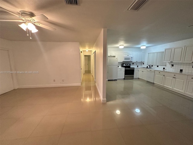 2165 SE Floresta Dr, Port St Lucie, FL 34984 - kitchen with white appliances, white cabinets, light countertops, ceiling fan, and decorative backsplash