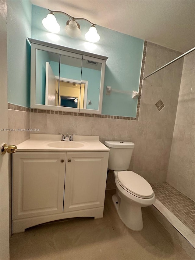 2165 SE Floresta Dr, Port St Lucie, FL 34984 - full bathroom featuring tile walls, tiled shower, toilet, vanity, and tile patterned flooring