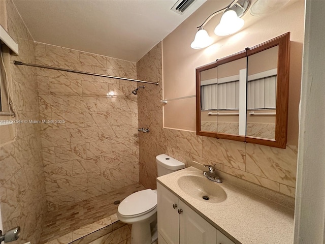 bathroom featuring toilet, vanity, backsplash, tile walls, and a tile shower