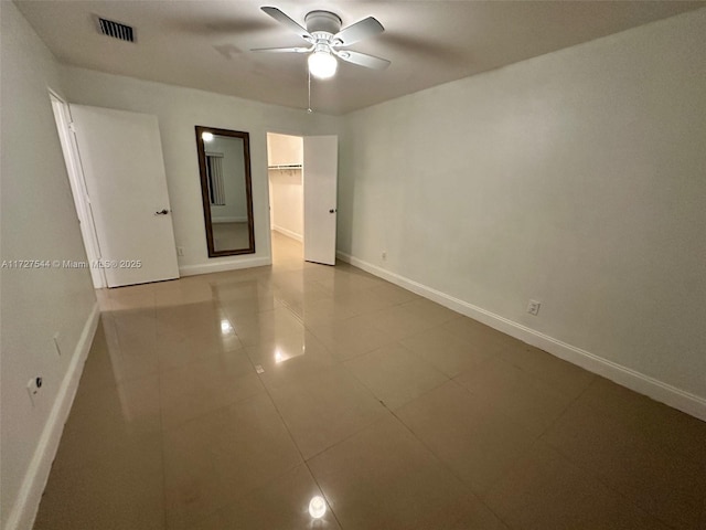2165 SE Floresta Dr, Port St Lucie, FL 34984 - unfurnished bedroom with baseboards, a walk in closet, ceiling fan, and tile patterned flooring