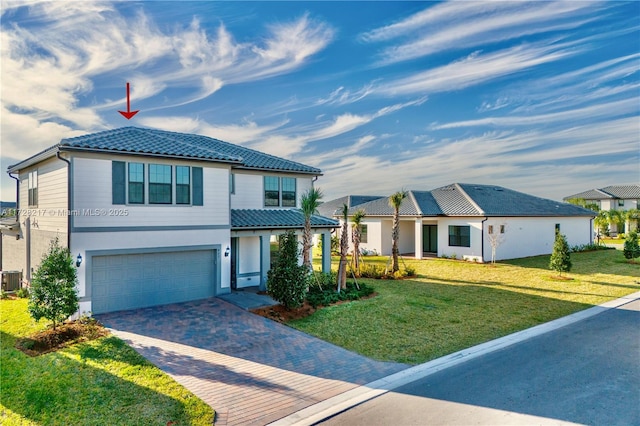 view of front facade featuring a garage, a tile roof, a front lawn, and decorative driveway