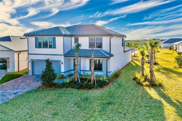 view of front of property featuring a garage, a tile roof, decorative driveway, a front yard, and stucco siding