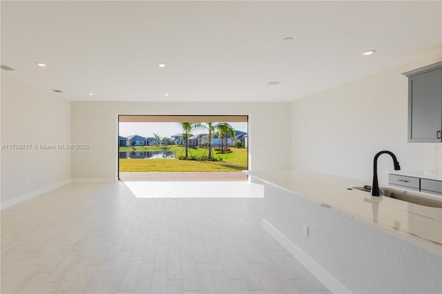 interior space featuring baseboards, light wood finished floors, a sink, and recessed lighting