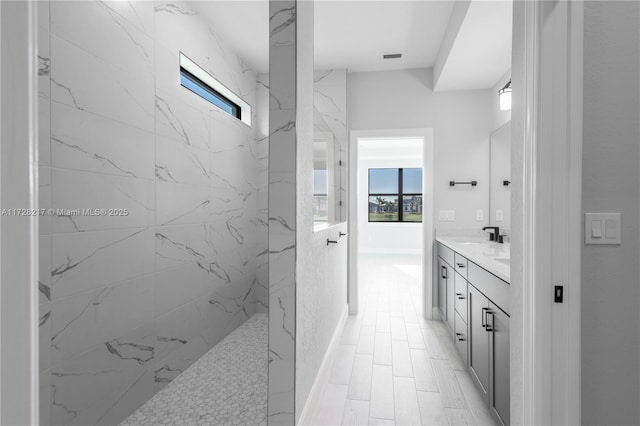 full bath featuring a wealth of natural light, a marble finish shower, and vanity