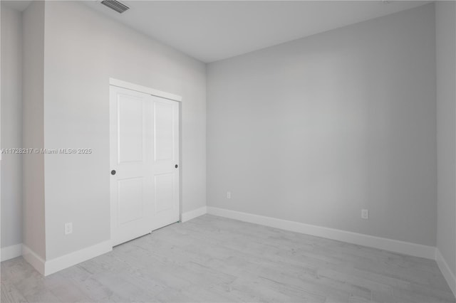 unfurnished bedroom with light wood-style floors, baseboards, visible vents, and a closet