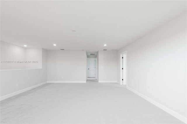 empty room featuring light carpet, baseboards, and recessed lighting