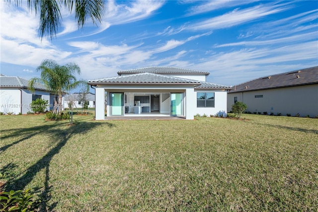 back of house featuring a lawn, a patio area, a tile roof, and stucco siding