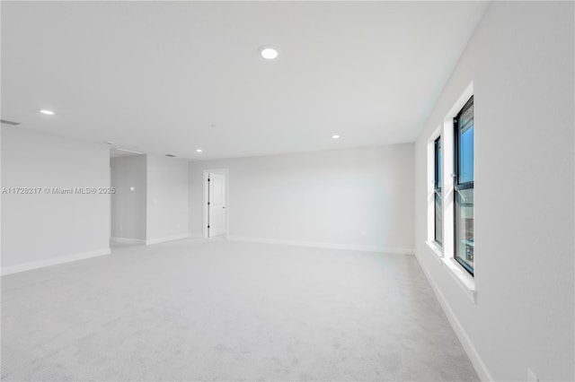 empty room featuring recessed lighting, light carpet, and baseboards