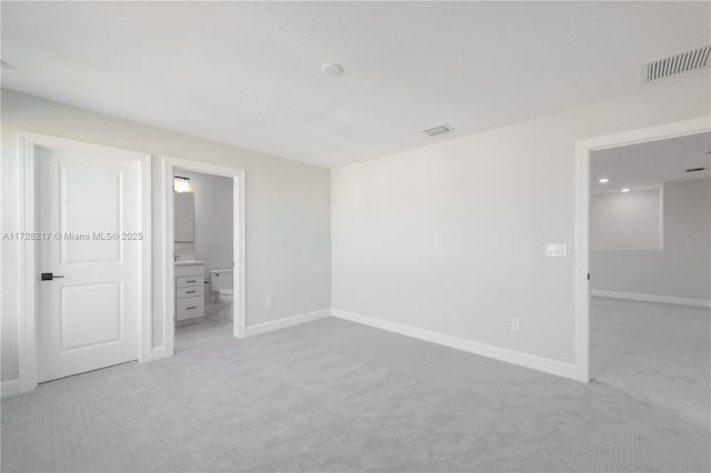 unfurnished bedroom with visible vents, connected bathroom, light carpet, and baseboards